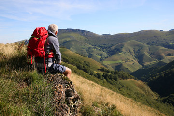 Hiker sitting on a rock admiring Basque Country scenery
