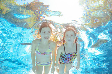 Fototapeta na wymiar Children swim in pool or sea underwater, happy active girls have fun in water, kids sport 