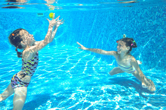 Children swim in pool underwater, happy active girls have fun in water
