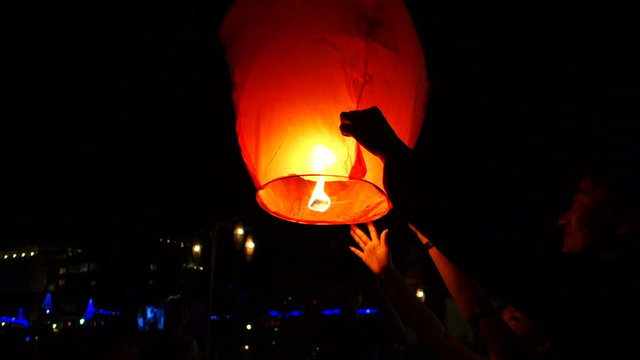 People start a paper lantern at night sky