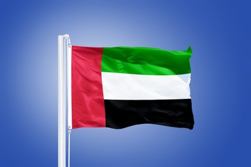 Fototapeta na wymiar Flag of United Arab Emirates flying against a blue sky
