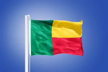 Flag of Benin flying against a blue sky