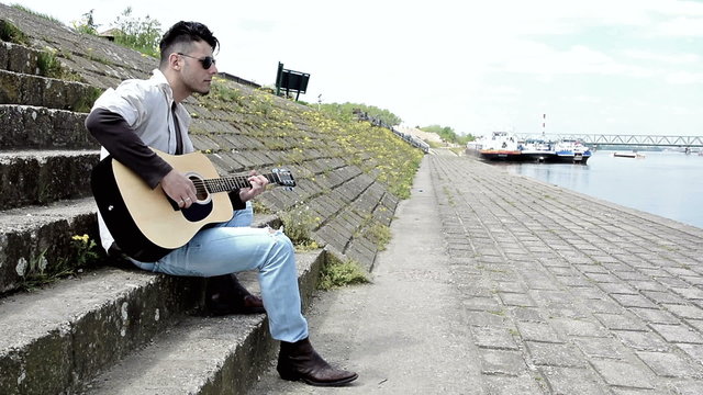 Man playing acustic guitar at the docks