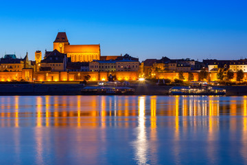 Old town of Torun at night reflected in Vistula river, Poland