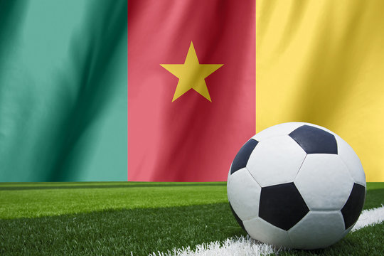 Soccer ball and national flag of Cameroon lies on the green gras
