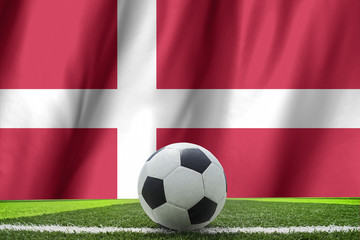 Fototapeta premium Soccer ball and national flag of Denmark lies on the green grass