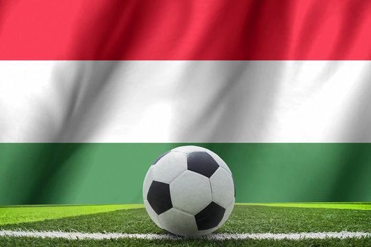 Soccer ball and national flag of Hungary lies on the green grass