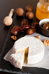 Camembert with honey, dates and nuts on dark background