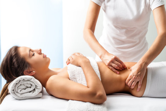 Therapist doing healing massage on female abdomen.