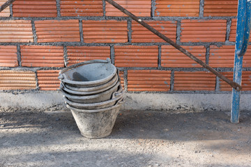 Cement buckets and red brick wall background at construction sit