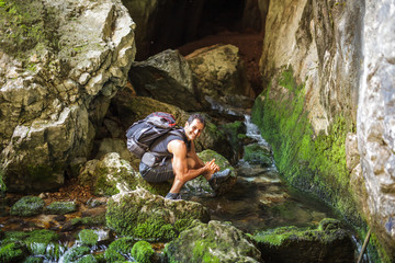 Tourist man washing hands in a mountain river