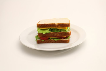 Prosciutto sandwich with vegetables and cheddar cheese on white plate