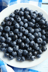 Blueberries in plate on a blue wooden background