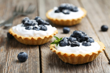 Dessert tartlets with blueberries on grey wooden background