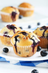 Tasty blueberry muffins on a white wooden background