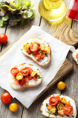 Tasty fresh bruschetta with cucumber on cutting board on grey wo