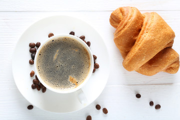 Delicious croissants with cup of coffee on white wooden backgrou