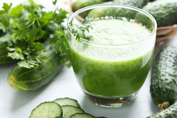 Glass of fresh cucumber juice on white wooden table