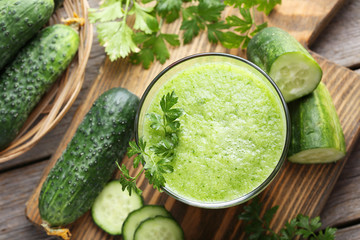 Glass of fresh cucumber juice on grey wooden table