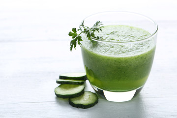 Glass of fresh cucumber juice on white wooden table