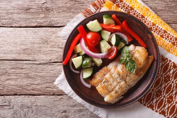 Photo sur Plexiglas Poisson Grilled white fish and fresh vegetable salad. horizontal top view  