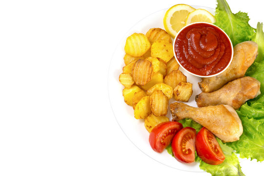 chicken legs on a white plate with slices of tomato and lettuce and french fries and ketchup top view isolated on white background
