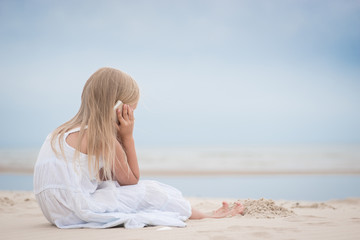 Fototapeta na wymiar Beautiful young girl talking on the phone at the seaside