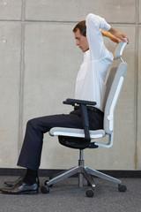stretching with chair in office - business man exercising