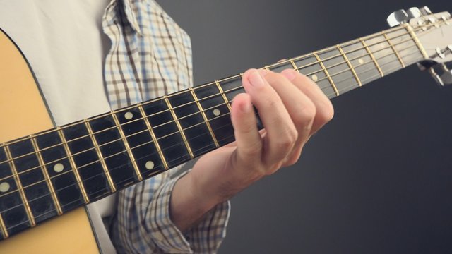 Musician playing rock tune on acoustic guitar, unplugged blues rock music performance indoors, close up, 4k uhd footage.