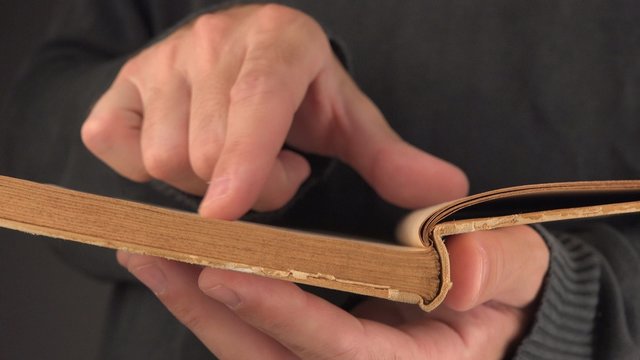 Man searching text and valuable information in old vintage book with yellow pages, close up image with selective focus, 4k uhd footage