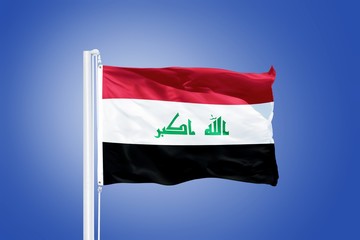 Naklejka na ściany i meble Flag of Iraq flying against a blue sky