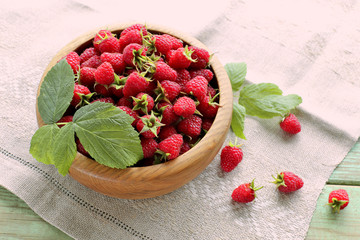 Raspberries with leaf in wooden bowl