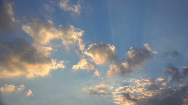 The sun lights up the clouds with warm colors as it sets on a summer day
