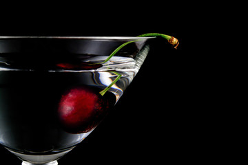 glass of drink with cherry closeup isolated on black background
