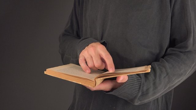 Man searching text and valuable information in old vintage book with yellow pages, close up image with selective focus, 4k uhd footage