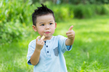 Little boy eat with his snack and thumb up