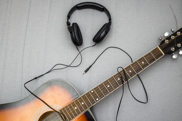 guitar lying on the sofa and lie next to the headphones, the wire from which form the silhouette of a guitarist playing