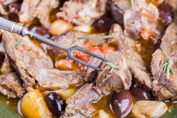 Lamb meat cooked in a tagine with olives, garlic, lemon and rosemary.