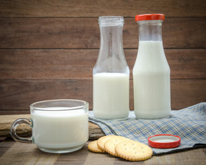 Milk bottle, milk glass and cookie put on wooden.