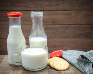 Milk bottle, milk glass and cookie put on wooden.