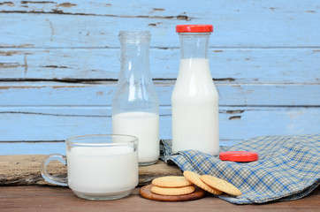 Milk bottle, milk glass and cookie put on old wood.