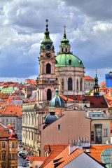 Blick über die leuchtenden Dächer von Prag in der Tschechischen Republik mit einem dramatischen Wolkenhimmel und Blick auf die Kirche des heiligen St. Nikolaus