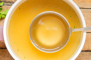 Spoon with bouillon to the pan with bouillon background