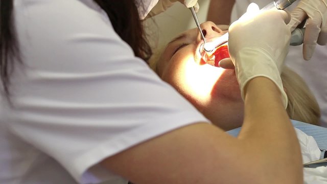 Dentist curing a female patient
