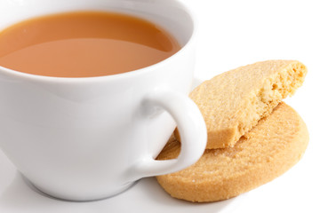 Detail of a white ceramic cup of tea with shortbread biscuits.