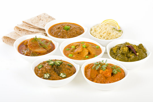 Vegetarian Curries - Selection of South Asian vegetarian curries in white bowls. Paneer Makhani, Palak Paneer, Aloo Matar, Baigan Bharta, Chilli Potatoes and Bhindi Masala, Pilau Rice and Chapattis.
