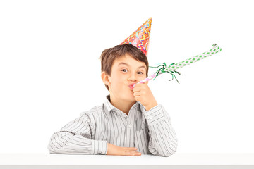 Little kid with party hat blowing a favor horn