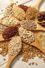 cereals in the spoons on the white wooden table background
