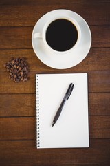 Cup of coffee and notepad with pen