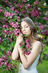 Young spring fashion woman. Trendy girl in the flowering trees i
